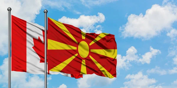 Bandeira do Canadá e Macedônia acenando no vento contra o céu azul nublado branco juntos. Conceito de diplomacia, relações internacionais . — Fotografia de Stock