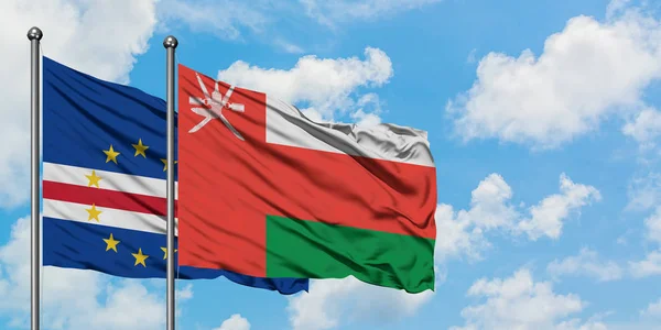 Bandera de Cabo Verde y Omán ondeando en el viento contra el cielo azul nublado blanco juntos. Concepto diplomático, relaciones internacionales . — Foto de Stock