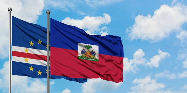 Bandera de Cabo Verde y Haití ondeando en el viento contra el cielo azul nublado blanco juntos. Concepto diplomático, relaciones internacionales . — Foto de Stock