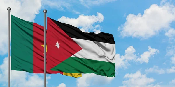 Bandera de Camerún y Jordania ondeando en el viento contra el cielo azul nublado blanco juntos. Concepto diplomático, relaciones internacionales . — Foto de Stock