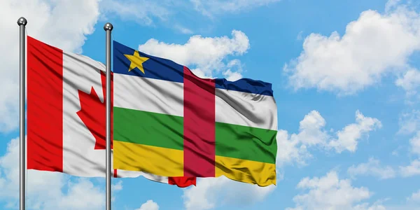 Bandera de Canadá y República Centroafricana ondeando en el viento contra el cielo azul nublado blanco juntos. Concepto diplomático, relaciones internacionales . — Foto de Stock