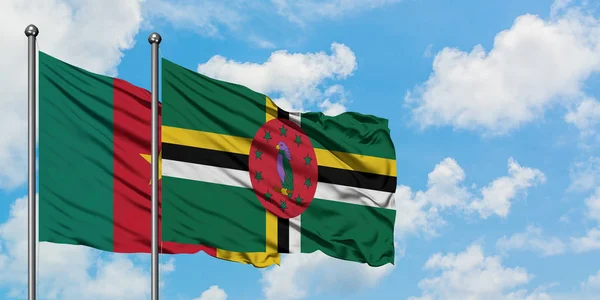 Bandera de Camerún y Dominica ondeando en el viento contra el cielo azul nublado blanco juntos. Concepto diplomático, relaciones internacionales . — Foto de Stock
