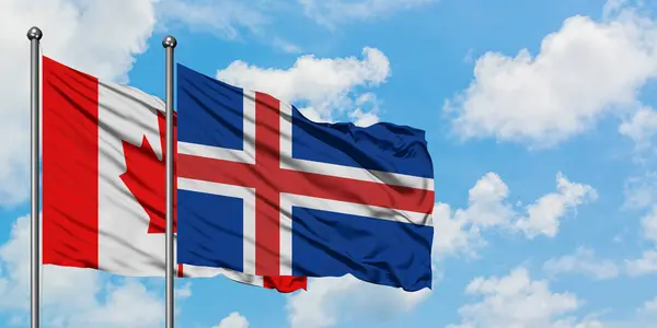 Bandera de Canadá e Islandia ondeando en el viento contra el cielo azul nublado blanco juntos. Concepto diplomático, relaciones internacionales . — Foto de Stock