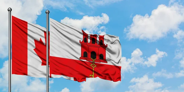 Bandera de Canadá y Gibraltar ondeando en el viento contra el cielo azul nublado blanco juntos. Concepto diplomático, relaciones internacionales . — Foto de Stock