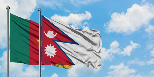 Bandera de Camerún y Nepal ondeando en el viento contra el cielo azul nublado blanco juntos. Concepto diplomático, relaciones internacionales . — Foto de Stock