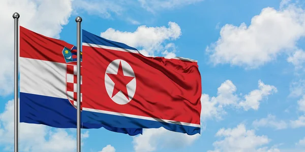 Vlajka Chorvatska a Severní Koreje se ve větru mávala proti bíle zatažené modré obloze. Diplomacie, mezinárodní vztahy. — Stock fotografie