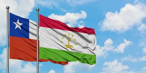 Bandera de Chile y Tayikistán ondeando en el viento contra el cielo azul nublado blanco juntos. Concepto diplomático, relaciones internacionales . — Foto de Stock