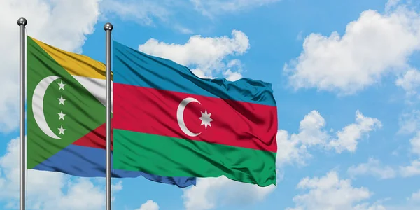 Comoras y la bandera de Azerbaiyán ondeando en el viento contra el cielo azul nublado blanco juntos. Concepto diplomático, relaciones internacionales . — Foto de Stock