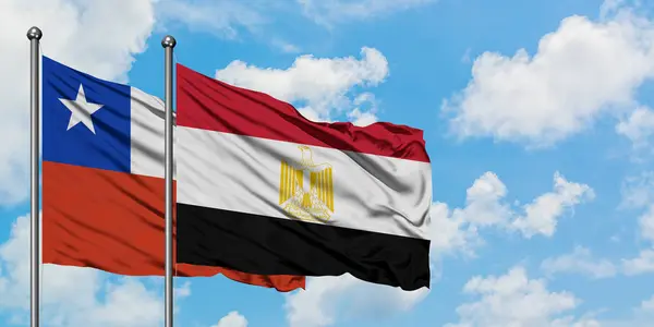 Bandera de Chile y Egipto ondeando en el viento contra el cielo azul nublado blanco juntos. Concepto diplomático, relaciones internacionales . — Foto de Stock