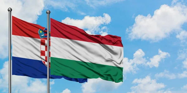 Bandera de Croacia y Hungría ondeando en el viento contra el cielo azul nublado blanco juntos. Concepto diplomático, relaciones internacionales . — Foto de Stock