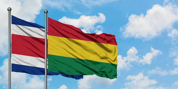 Costa Rica en Bolivia vlag zwaaien in de wind tegen witte bewolkte blauwe hemel samen. Diplomatie concept, internationale betrekkingen. — Stockfoto