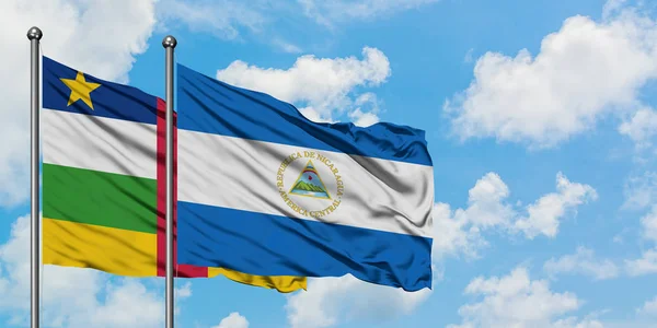 Orta Afrika Cumhuriyeti ve Nikaragua bayrağı birlikte beyaz bulutlu mavi gökyüzüne karşı rüzgarda sallayarak. Diplomasi kavramı, uluslararası ilişkiler. — Stok fotoğraf