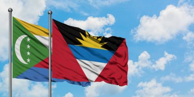 Komorlar ve Antigua ve Barbuda bayrağı birlikte beyaz bulutlu mavi gökyüzüne karşı rüzgarda sallayarak. Diplomasi kavramı, uluslararası ilişkiler.