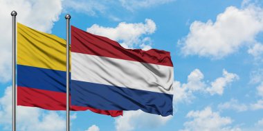 Kolombiya ve Hollanda bayrağı birlikte beyaz bulutlu mavi gökyüzüne karşı rüzgarsal sallayarak. Diplomasi kavramı, uluslararası ilişkiler.