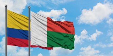 Kolombiya ve Madagaskar bayrağı birlikte beyaz bulutlu mavi gökyüzüne karşı rüzgarda sallayarak. Diplomasi kavramı, uluslararası ilişkiler.