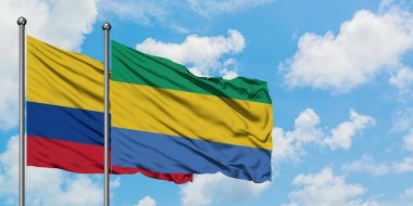 Kolombiya ve Gabon bayrağı birlikte beyaz bulutlu mavi gökyüzüne karşı rüzgarda sallayarak. Diplomasi kavramı, uluslararası ilişkiler.
