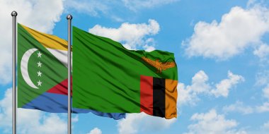 Komorlar ve Zambiya bayrağı birlikte beyaz bulutlu mavi gökyüzüne karşı rüzgarda sallayarak. Diplomasi kavramı, uluslararası ilişkiler.