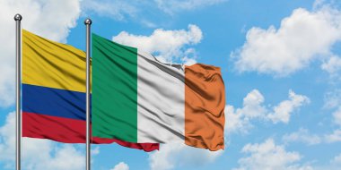 Kolombiya ve İrlanda bayrağı birlikte beyaz bulutlu mavi gökyüzüne karşı rüzgarda sallayarak. Diplomasi kavramı, uluslararası ilişkiler.