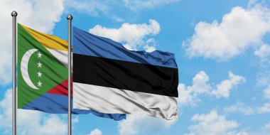 Komorlar ve Estonya bayrağı birlikte beyaz bulutlu mavi gökyüzüne karşı rüzgarda sallayarak. Diplomasi kavramı, uluslararası ilişkiler.