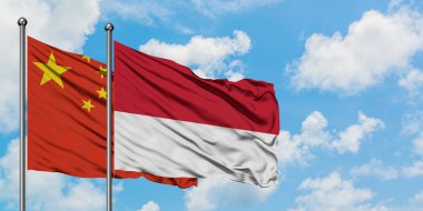 Çin ve Monako bayrağı birlikte beyaz bulutlu mavi gökyüzüne karşı rüzgarsal sallayarak. Diplomasi kavramı, uluslararası ilişkiler.