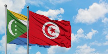 Komorlar ve Tunus bayrağı birlikte beyaz bulutlu mavi gökyüzüne karşı rüzgarda sallayarak. Diplomasi kavramı, uluslararası ilişkiler.