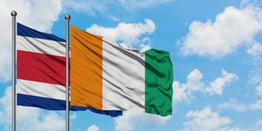 Kosta Rika ve Fildişi Sahili bayrağı birlikte beyaz bulutlu mavi gökyüzüne karşı rüzgarda sallayarak. Diplomasi kavramı, uluslararası ilişkiler.