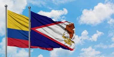 Kolombiya ve Amerikan Samoası bayrağı birlikte beyaz bulutlu mavi gökyüzüne karşı rüzgarda sallayarak. Diplomasi kavramı, uluslararası ilişkiler.