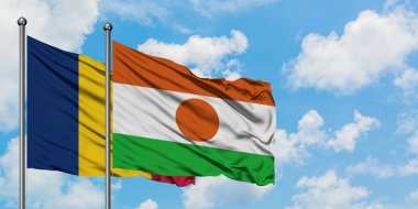 Çad ve Nijer bayrağı birlikte beyaz bulutlu mavi gökyüzüne karşı rüzgarda sallayarak. Diplomasi kavramı, uluslararası ilişkiler.