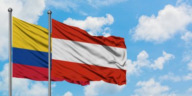 Kolombiya ve Avusturya bayrağı birlikte beyaz bulutlu mavi gökyüzüne karşı rüzgarda sallayarak. Diplomasi kavramı, uluslararası ilişkiler.