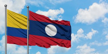 Kolombiya ve Laos bayrağı birlikte beyaz bulutlu mavi gökyüzüne karşı rüzgarda sallayarak. Diplomasi kavramı, uluslararası ilişkiler.