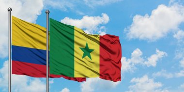 Kolombiya ve Senegal bayrağı birlikte beyaz bulutlu mavi gökyüzüne karşı rüzgarda sallayarak. Diplomasi kavramı, uluslararası ilişkiler.