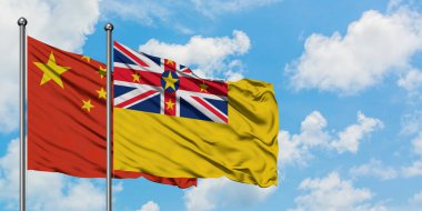 Çin ve Niue bayrağı birlikte beyaz bulutlu mavi gökyüzüne karşı rüzgarda sallayarak. Diplomasi kavramı, uluslararası ilişkiler.