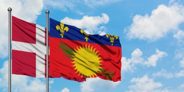 Danimarka ve Guadeloupe bayrağı birlikte beyaz bulutlu mavi gökyüzüne karşı rüzgarda sallayarak. Diplomasi kavramı, uluslararası ilişkiler.