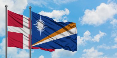 Danimarka ve Marshall Adaları bayrağı birlikte beyaz bulutlu mavi gökyüzüne karşı rüzgarda sallayarak. Diplomasi kavramı, uluslararası ilişkiler.