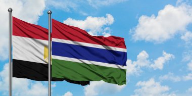 Mısır ve Gambiya bayrağı birlikte beyaz bulutlu mavi gökyüzüne karşı rüzgarda sallayarak. Diplomasi kavramı, uluslararası ilişkiler.