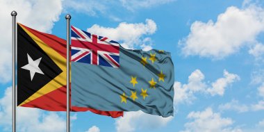 Doğu Timor ve Tuvalu bayrağı birlikte beyaz bulutlu mavi gökyüzüne karşı rüzgarda sallayarak. Diplomasi kavramı, uluslararası ilişkiler.