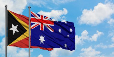 Doğu Timor ve Avustralya bayrağı birlikte beyaz bulutlu mavi gökyüzüne karşı rüzgarda sallayarak. Diplomasi kavramı, uluslararası ilişkiler.