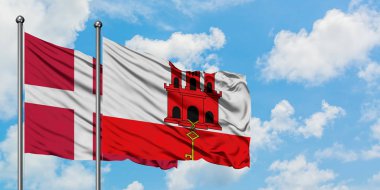 Danimarka ve Cebelitarık bayrağı birlikte beyaz bulutlu mavi gökyüzüne karşı rüzgarda sallayarak. Diplomasi kavramı, uluslararası ilişkiler.