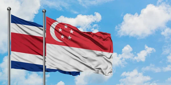 Costa rica und singapore flagge wehen gemeinsam im wind vor weißem wolkenblauem himmel. Diplomatie-Konzept, internationale Beziehungen. — Stockfoto