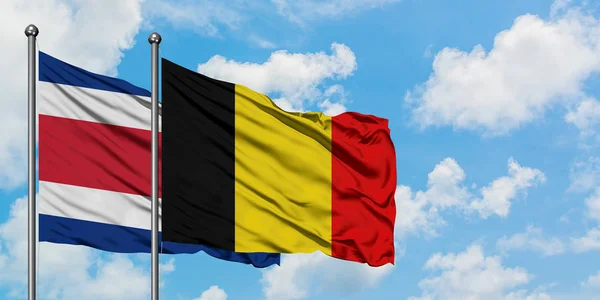 哥斯达黎加和比利时国旗在风中飘扬，与白云蓝天相一起。外交概念、国际关系. — 图库照片