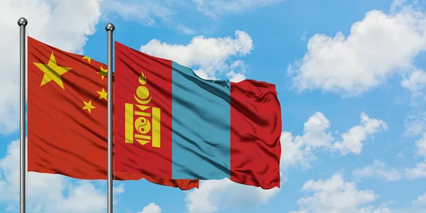 Kina og Mongoliet flag vinker i vinden mod hvid overskyet blå himmel sammen. Diplomati koncept, internationale relationer . - Stock-foto