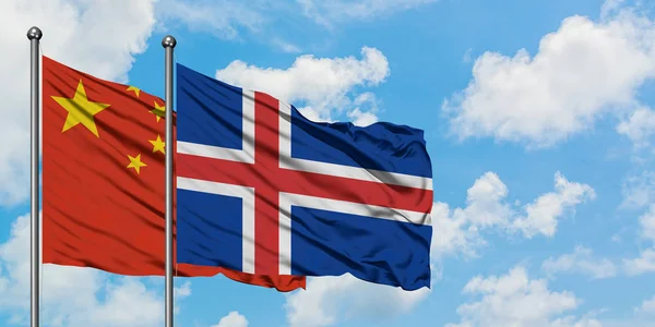 Chiny i Islandia flaga machając w wiatr przed białym zachmurzone błękitne niebo razem. Koncepcja dyplomacji, stosunki międzynarodowe. — Zdjęcie stockowe