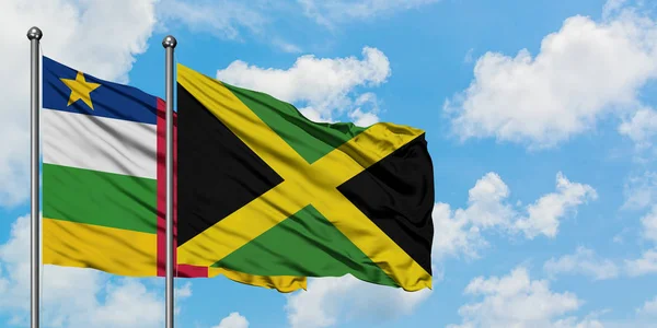 Bandera de la República Centroafricana y Jamaica ondeando en el viento contra el cielo azul nublado blanco juntos. Concepto diplomático, relaciones internacionales . — Foto de Stock