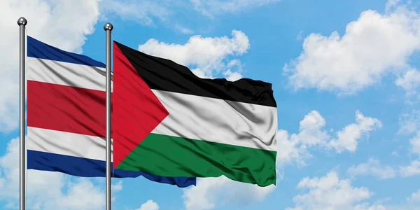 Drapeau du Costa Rica et de la Palestine agitant dans le vent contre ciel bleu nuageux blanc ensemble. Concept de diplomatie, relations internationales . — Photo
