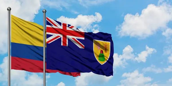 Bandera de Colombia y las Islas Turcas y Caicos ondeando en el viento contra el cielo azul nublado blanco juntos. Concepto diplomático, relaciones internacionales . — Foto de Stock