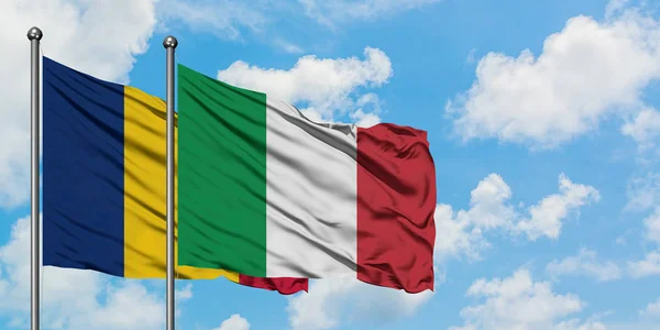 Bandera de Chad e Italia ondeando en el viento contra el cielo azul nublado blanco juntos. Concepto diplomático, relaciones internacionales . — Foto de Stock