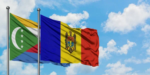 Bandera de las Comoras y Moldavia ondeando en el viento contra el cielo azul nublado blanco juntos. Concepto diplomático, relaciones internacionales . — Foto de Stock