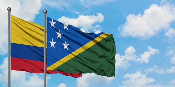 Colombia and Solomon Islands flag waving in the wind against white cloudy blue sky together. Diplomacy concept, international relations. — Stock Photo, Image