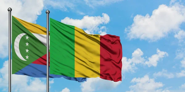 Bandera de las Comoras y Malí ondeando en el viento contra el cielo azul nublado blanco juntos. Concepto diplomático, relaciones internacionales . — Foto de Stock