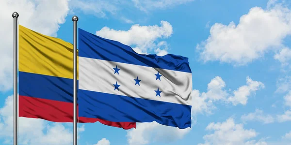 Colombia and Honduras flag waving in the wind against white cloudy blue sky together. Diplomacy concept, international relations. — Stock Photo, Image